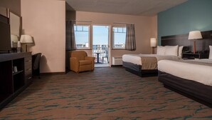 A hotel room with a bed, a desk with a chair, a small table with a chair, and a view of the outside through a door. - Gateway Hotel & Suites Ocean City, an Ascend Collection Hotel (Ocean City)