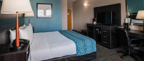 Ett hotellrum med en säng, ett skrivbord, en stol, en tv och en skrivbordslampa.