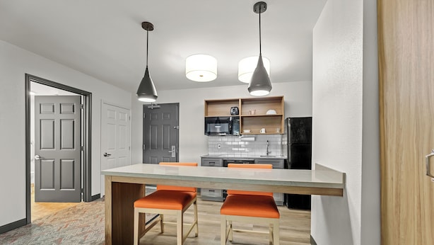 Una cocina moderna con una isla central, iluminación colgante y una puerta de madera.