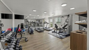 Un gimnasio con cintas de correr, máquinas de pesas y pelotas de ejercicio.
