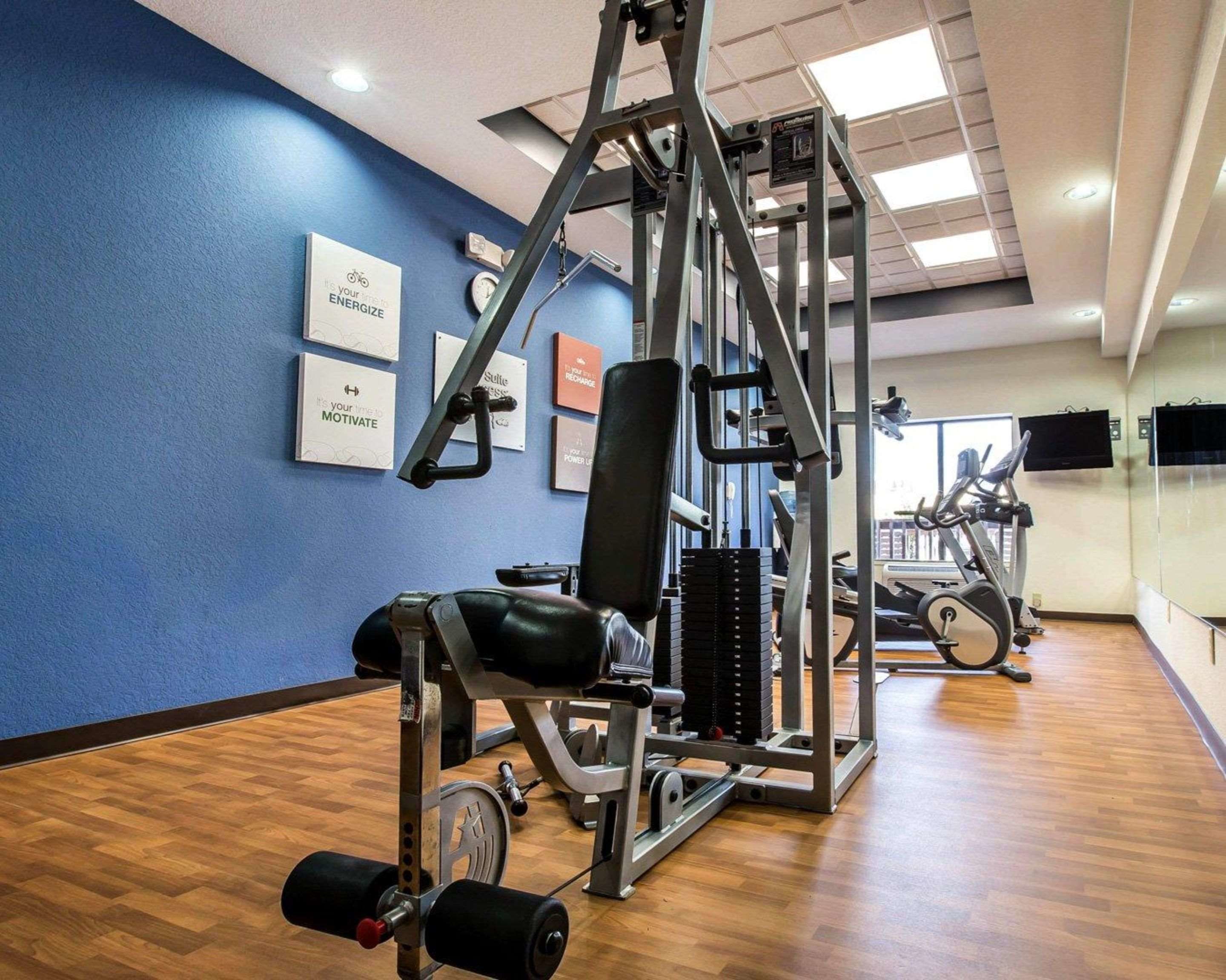 A gym with exercise equipment, a blue wall, and a wooden floor.