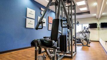A gym with exercise equipment, a blue wall, and a wooden floor.