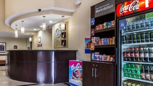 Rebedor d'hotel amb taulell de recepció, nevera de Coca-Cola i congelador ple d'aperitius.