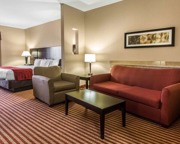 A hotel room with a bed, two armchairs, a sofa, a coffee table, and a painting on the wall.