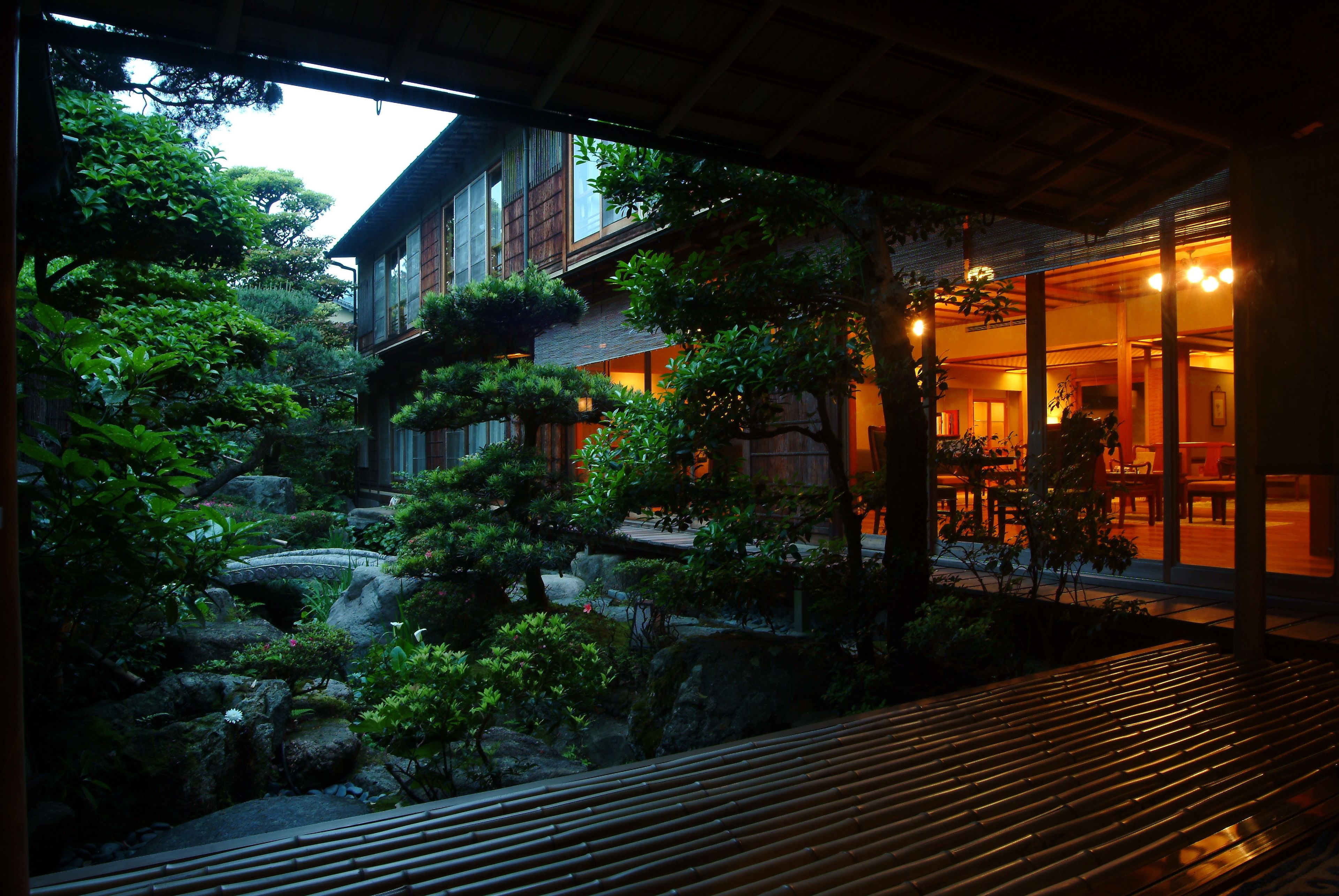 A traditional Japanese-style building with a wooden exterior, a rock garden, and a wooden deck.