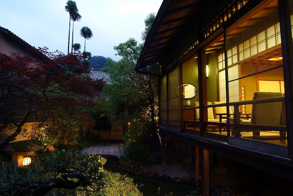 A traditional Japanese-style building with large windows and a garden area with a pond. - Nishimuraya Honkan (Toyooka)