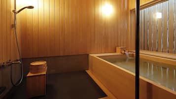 Un interior de madera con una bañera, ducha y retrete.