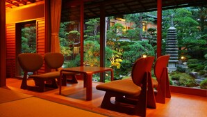 Una habitación tradicional japonesa con suelo de tatami, mesas de madera bajas y sillas.
