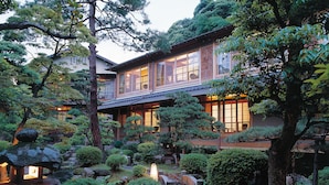 Un edificio japonés tradicional rodeado de vegetación exuberante y senderos de piedra.