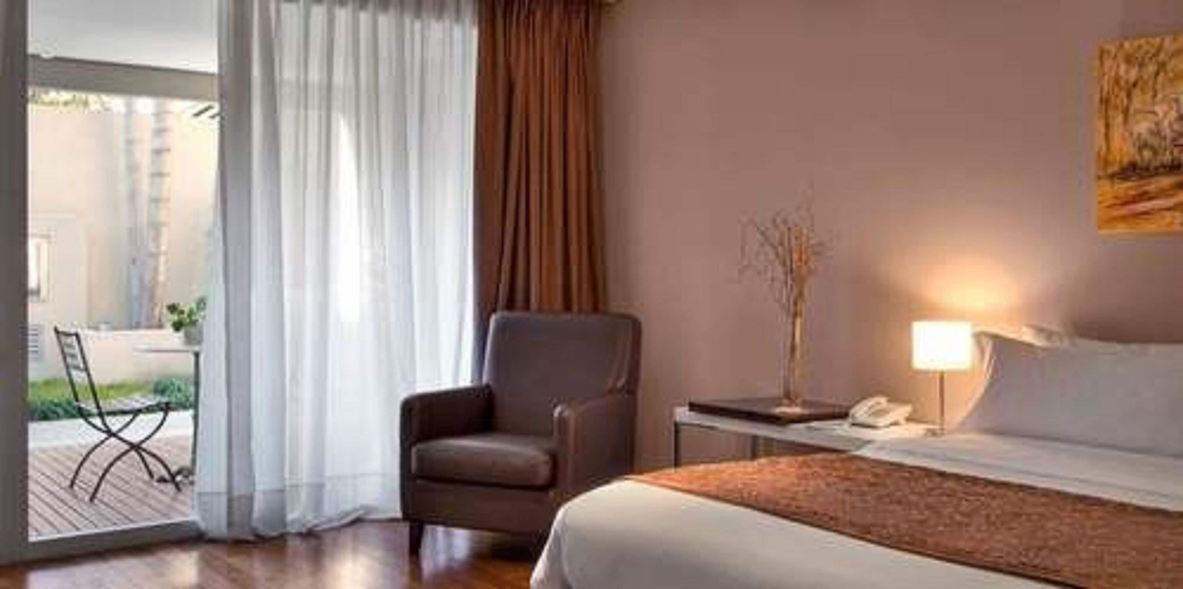 Une chambre d’hôtel avec un lit, une chaise, une table et une lampe.