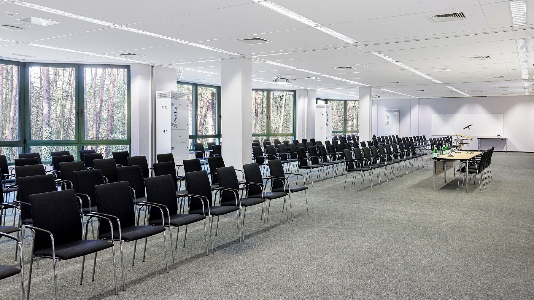 A conference room with rows of chairs, a projector, and air purifiers.