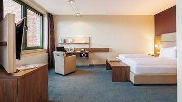 A hotel room with a bed, a desk, a chair, a TV, and a window with curtains.
