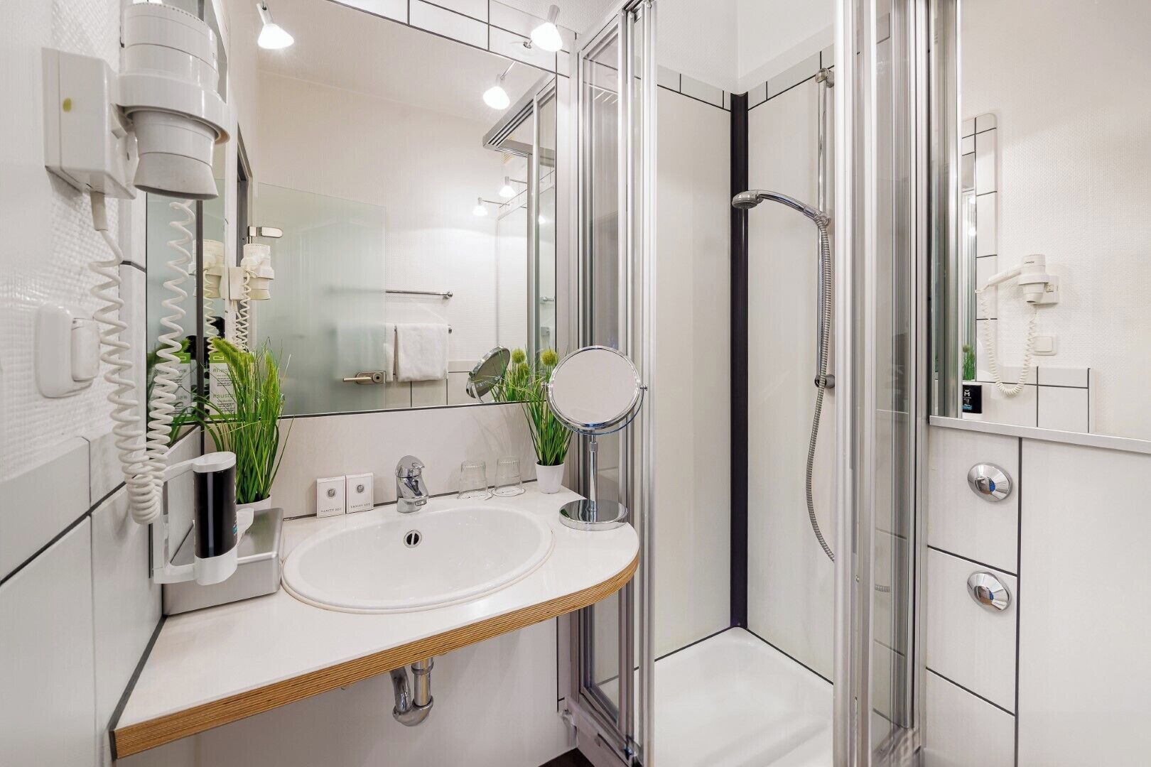A modern bathroom with a glass shower enclosure, a sink with a mirror, and a towel rack.