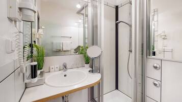 A modern bathroom with a glass shower enclosure, a sink with a mirror, and a towel rack.