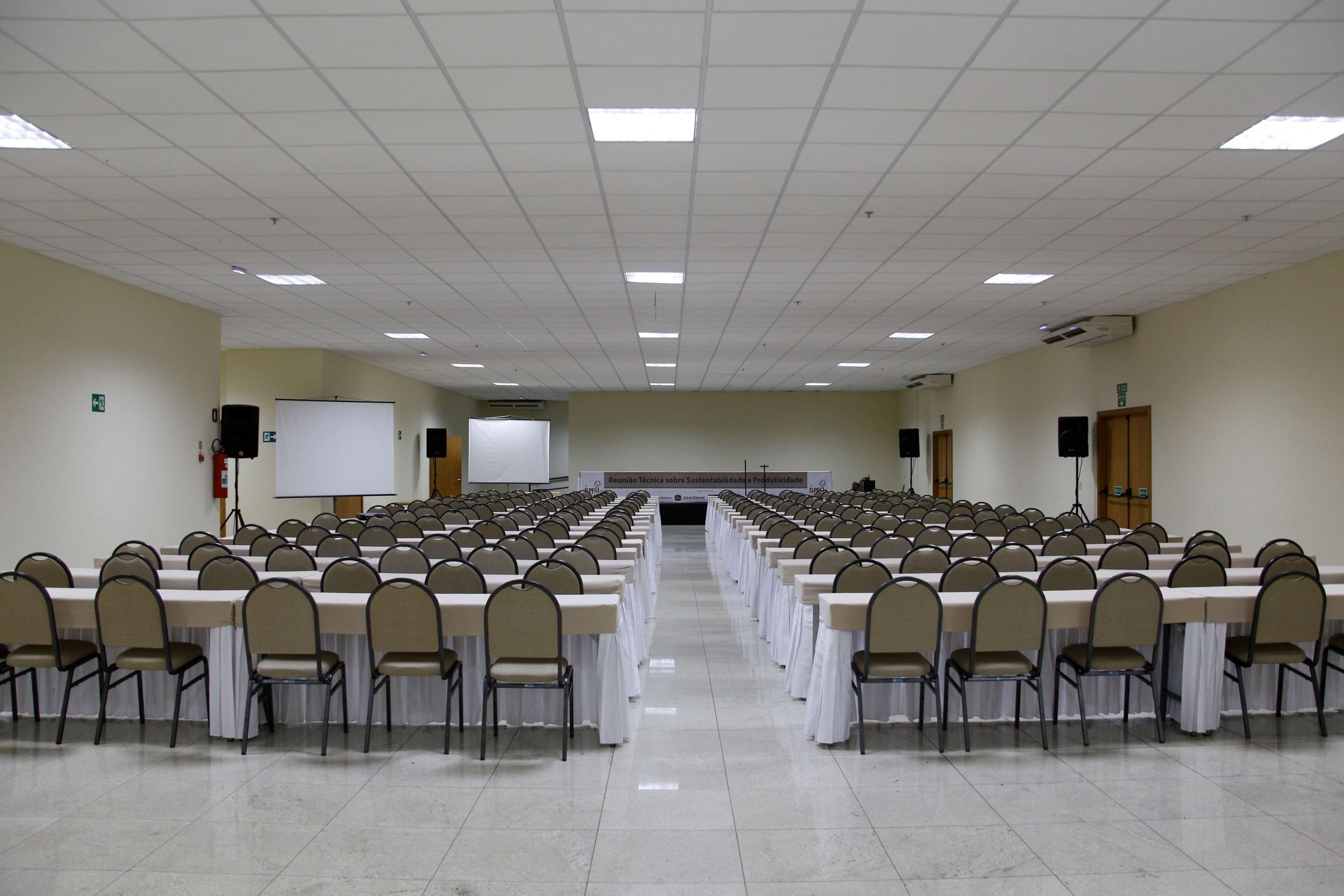 A conference room with rows of tables and chairs, a whiteboard, and a projector screen.