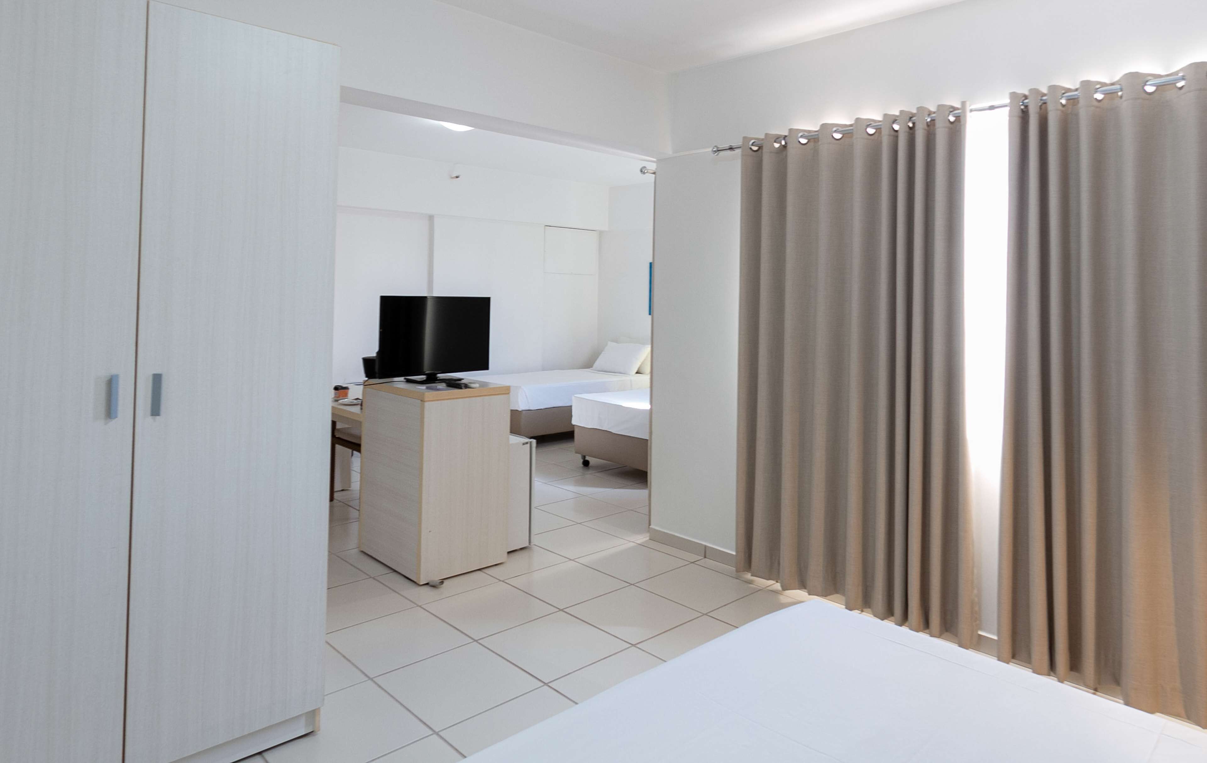 A hotel room with a bed, a desk, a television, and a wardrobe.