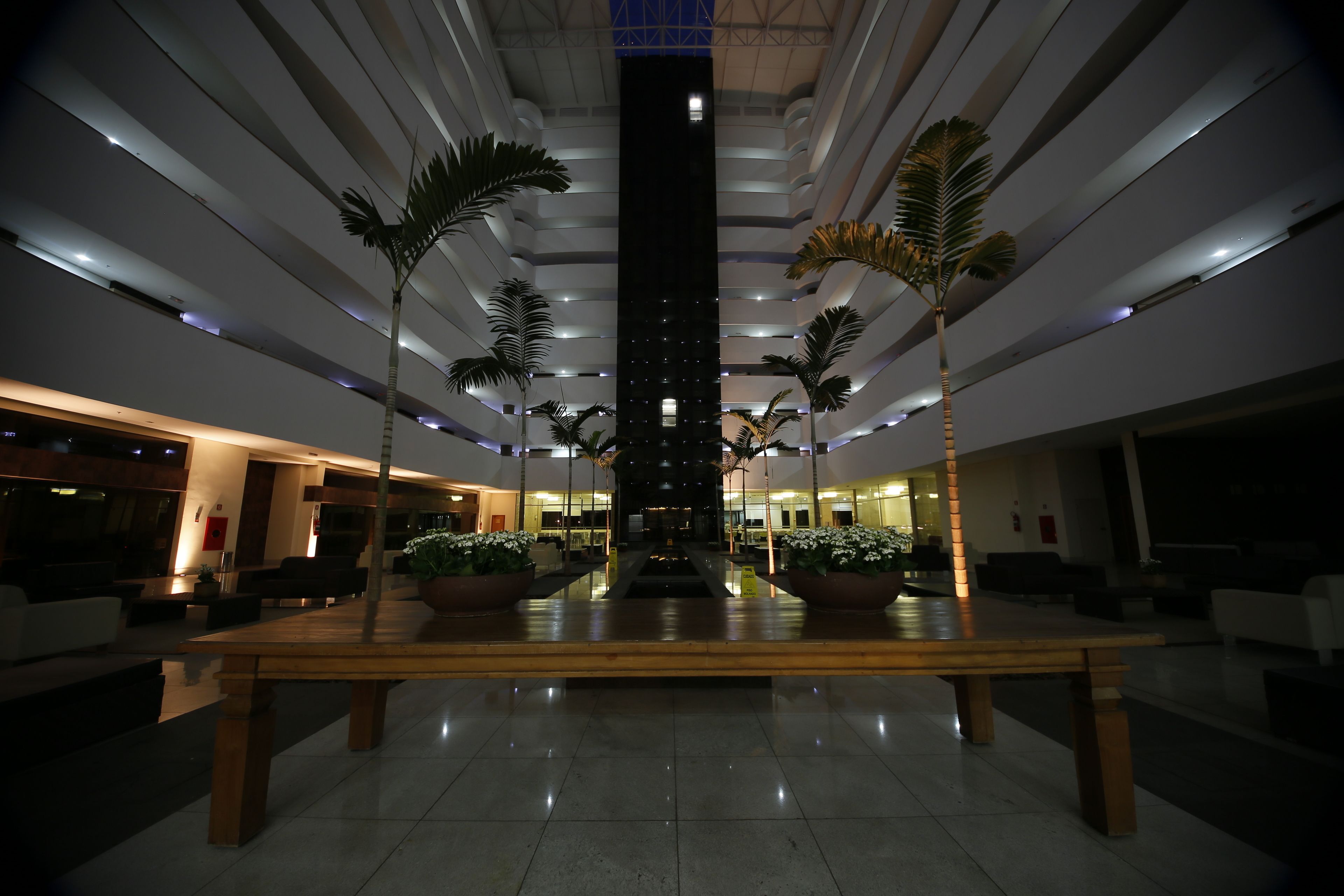 Un lobby espacioso con una fuente central, varias zonas de estar y altas palmeras.