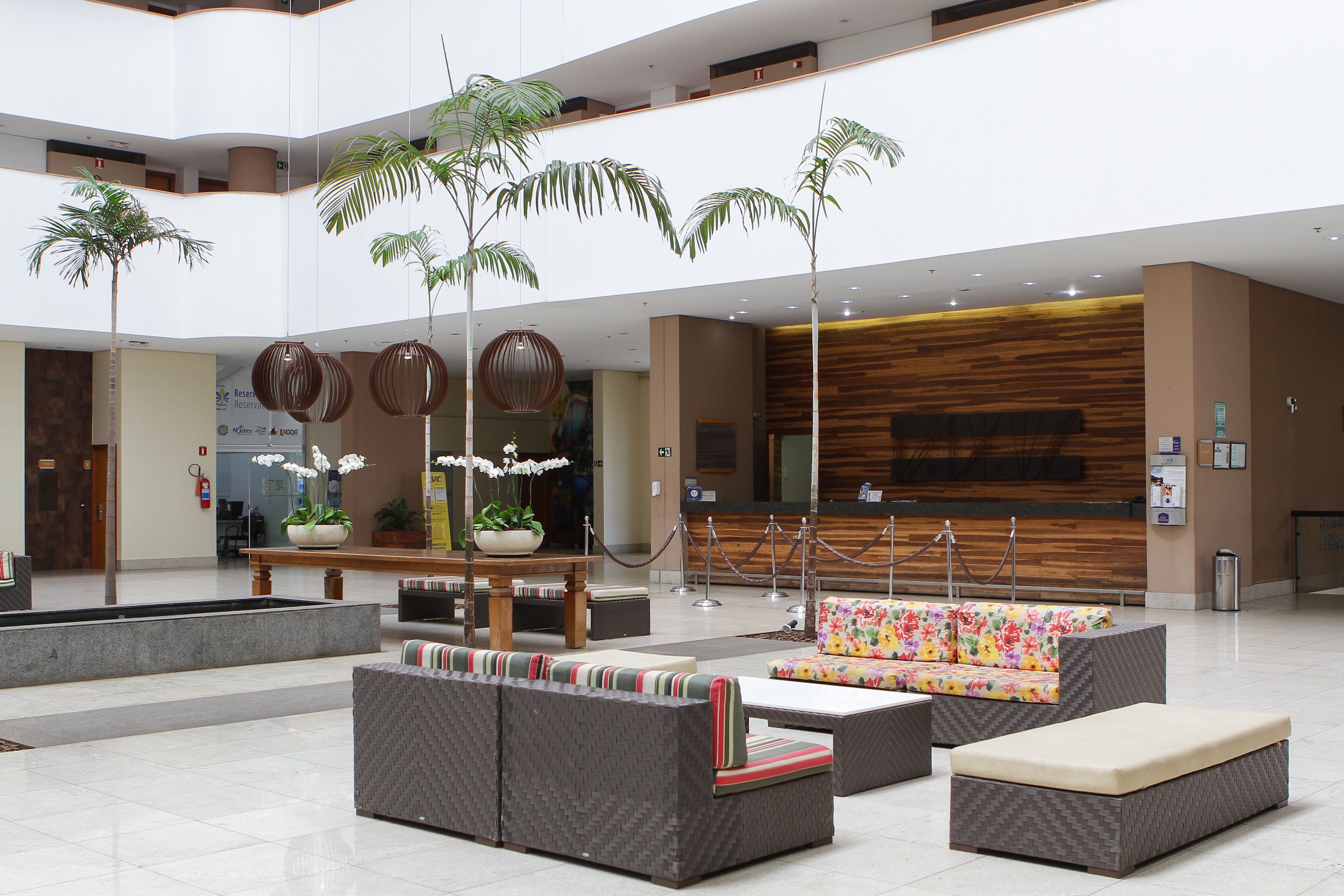 Un'ampia hall con reception, zone relax e piante decorative.