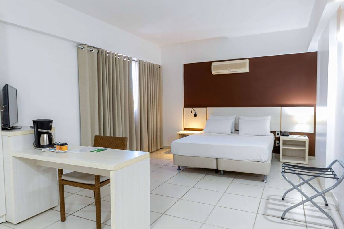 Una habitación de hotel con cama, escritorio, silla y televisión.