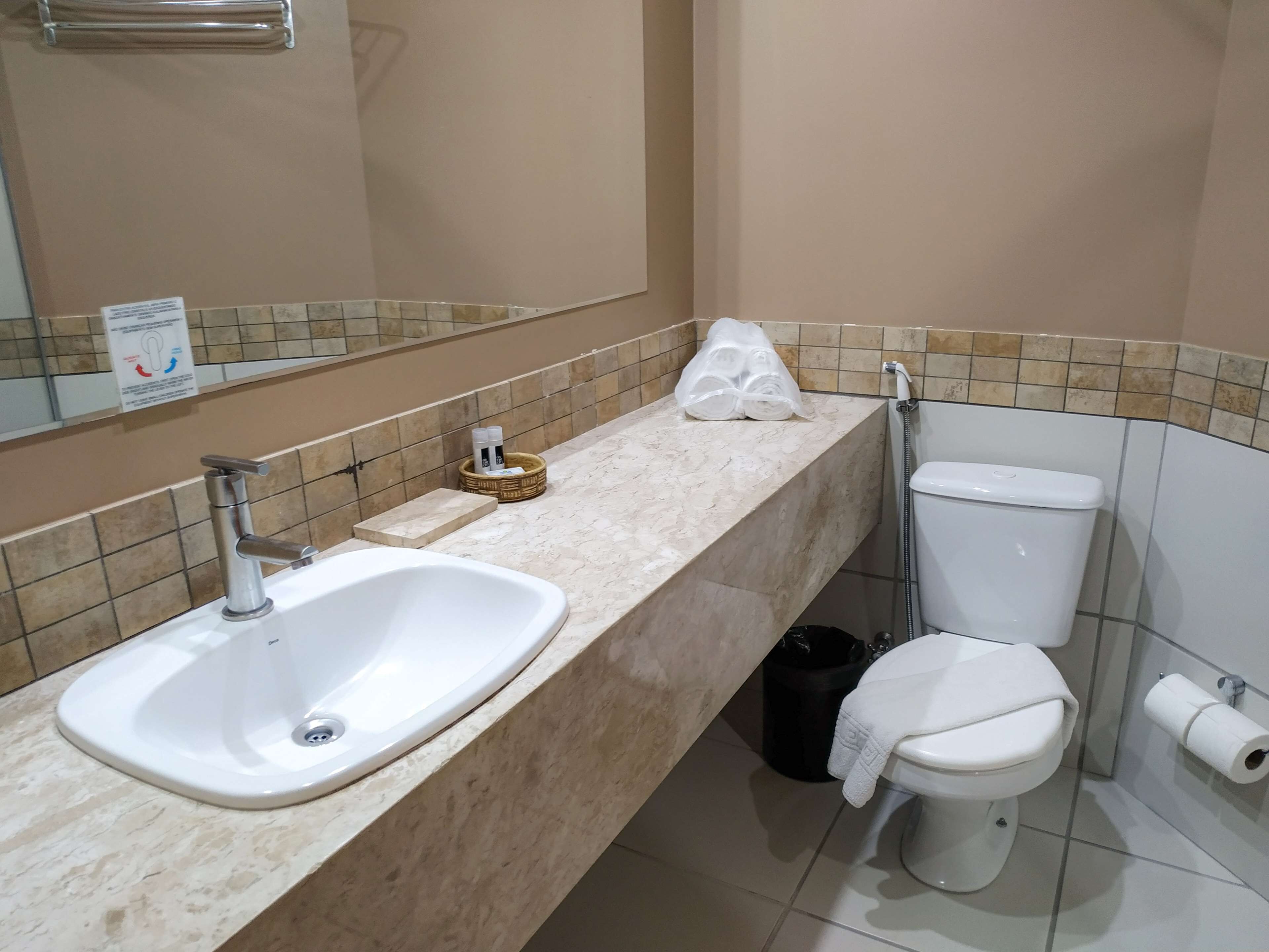 Une salle de bain équipée d’un lavabo, de toilettes et d’une poubelle.