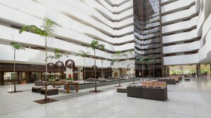Un vestíbulo amplio con varias zonas de estar, un techo alto y un diseño arquitectónico moderno.