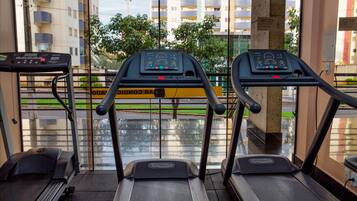 A gym with treadmills, a stationary bike, and a rowing machine.