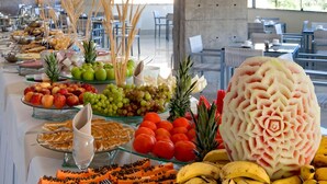 Un bufé con diversas frutas y verduras, como manzanas, uvas, tomates y plátanos.