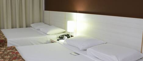 Ett hotellrum med två sängar, ett nattduksbord med en lampa och en telefon.