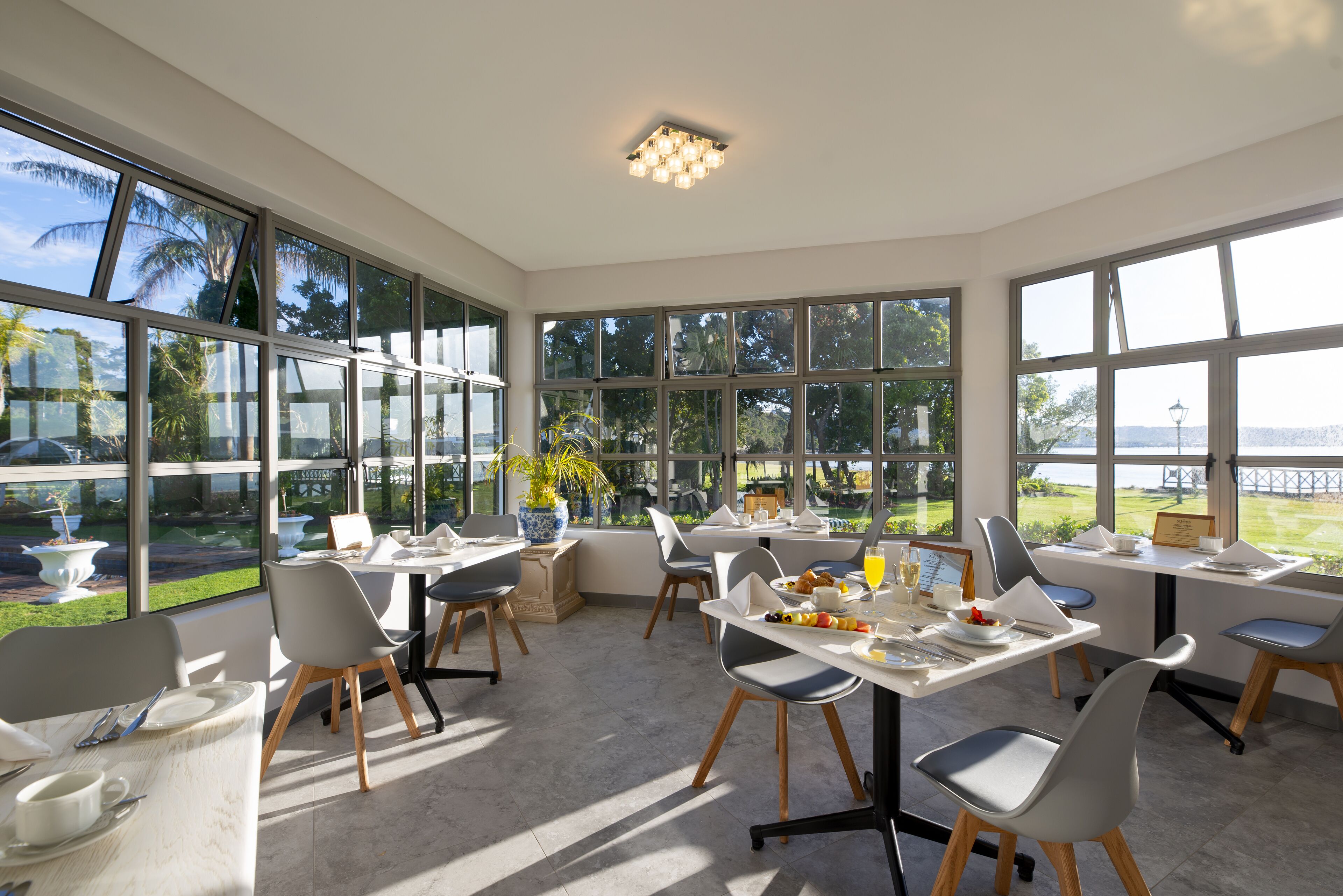 A bright dining area with large windows, modern furniture, and a view of the outdoors.