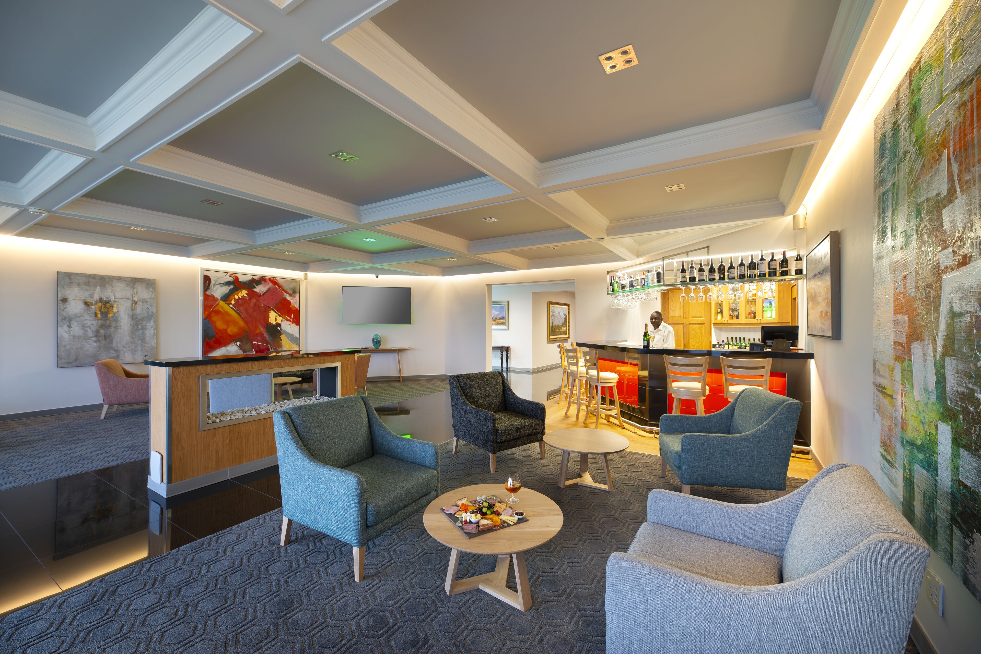 A modern hotel lobby with seating areas, a bar, and artwork on the walls.
