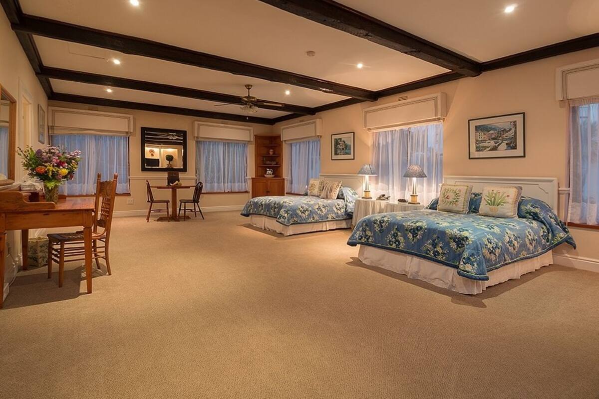 A spacious bedroom with two beds, a desk, and a dining area.