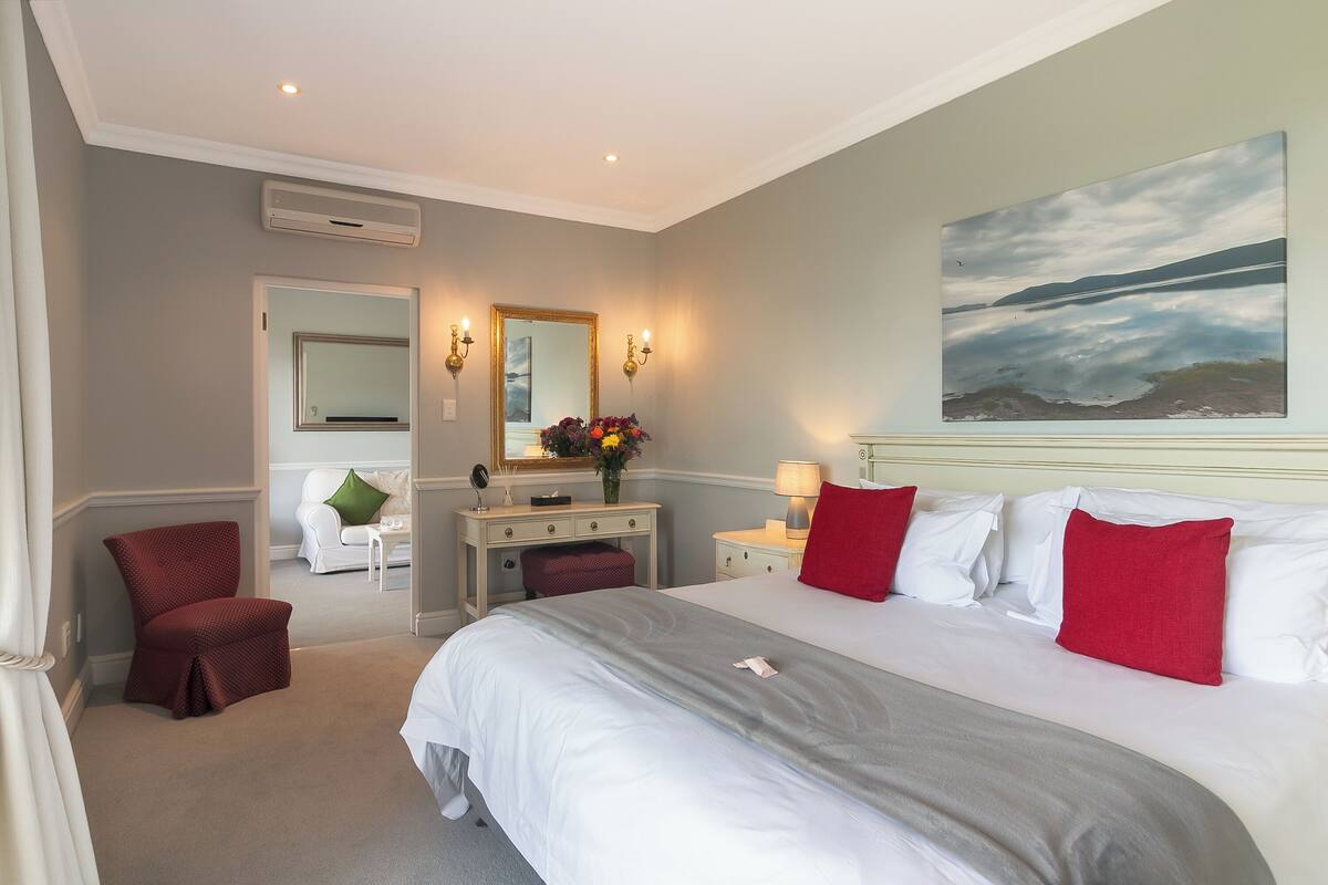 A hotel room with a large bed, a desk, a chair, and a painting on the wall.