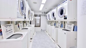 Een wasserette met meerdere wasmachines, elk met een bedieningspaneel en genummerd voor herkenning.