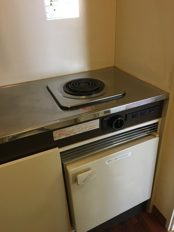 A compact kitchenette with a stove, a microwave, and a small refrigerator.