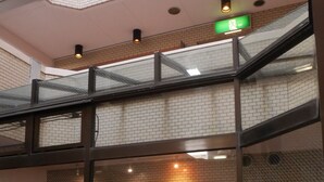 Een meerlaags atrium met glazen balustrades, een trap en een groen vluchtroutebord.