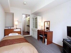 A hotel room with a bed, a desk with a chair, a television, and a wardrobe.