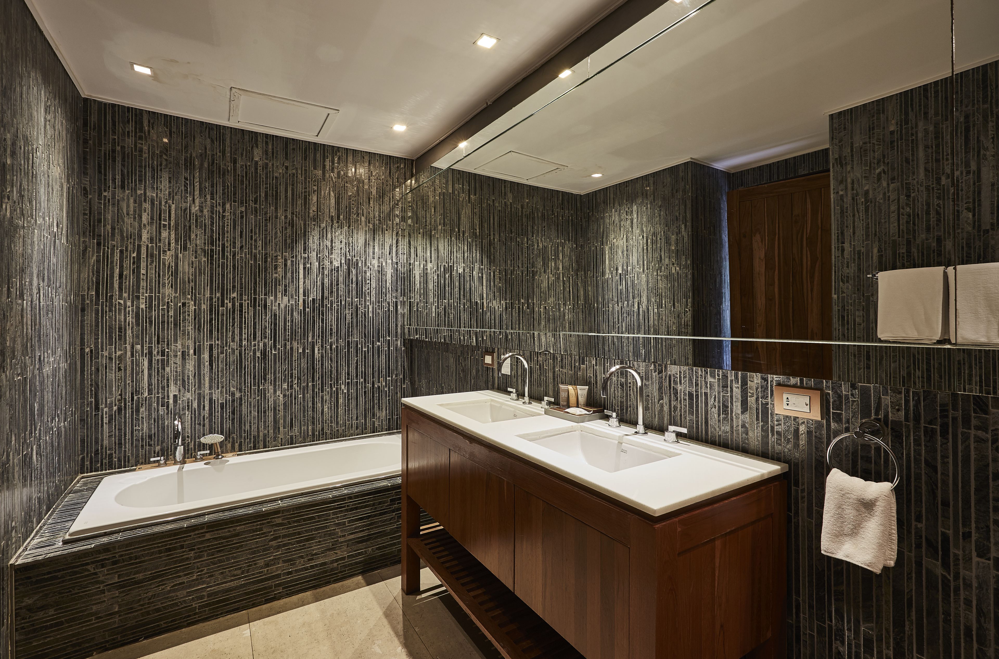 A modern bathroom with a large bathtub, double sinks, and a mirror above the sinks.