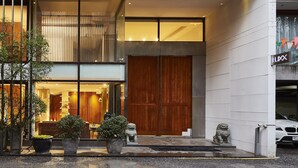 A modern building with a large wooden door, a balcony, and a sign reading "LUXX". - LUXX Langsuan Hotel (Bangkok)