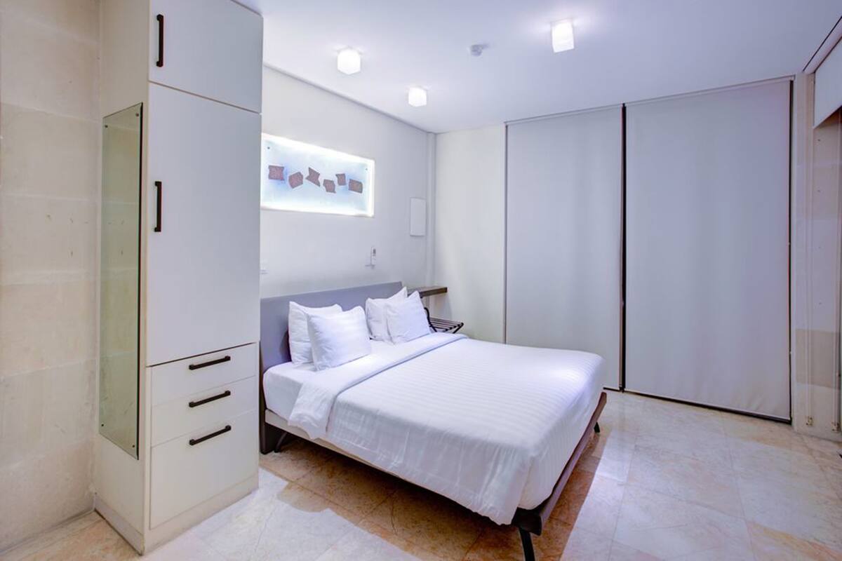 A modern bedroom with a bed, a wardrobe, and a wall-mounted artwork.