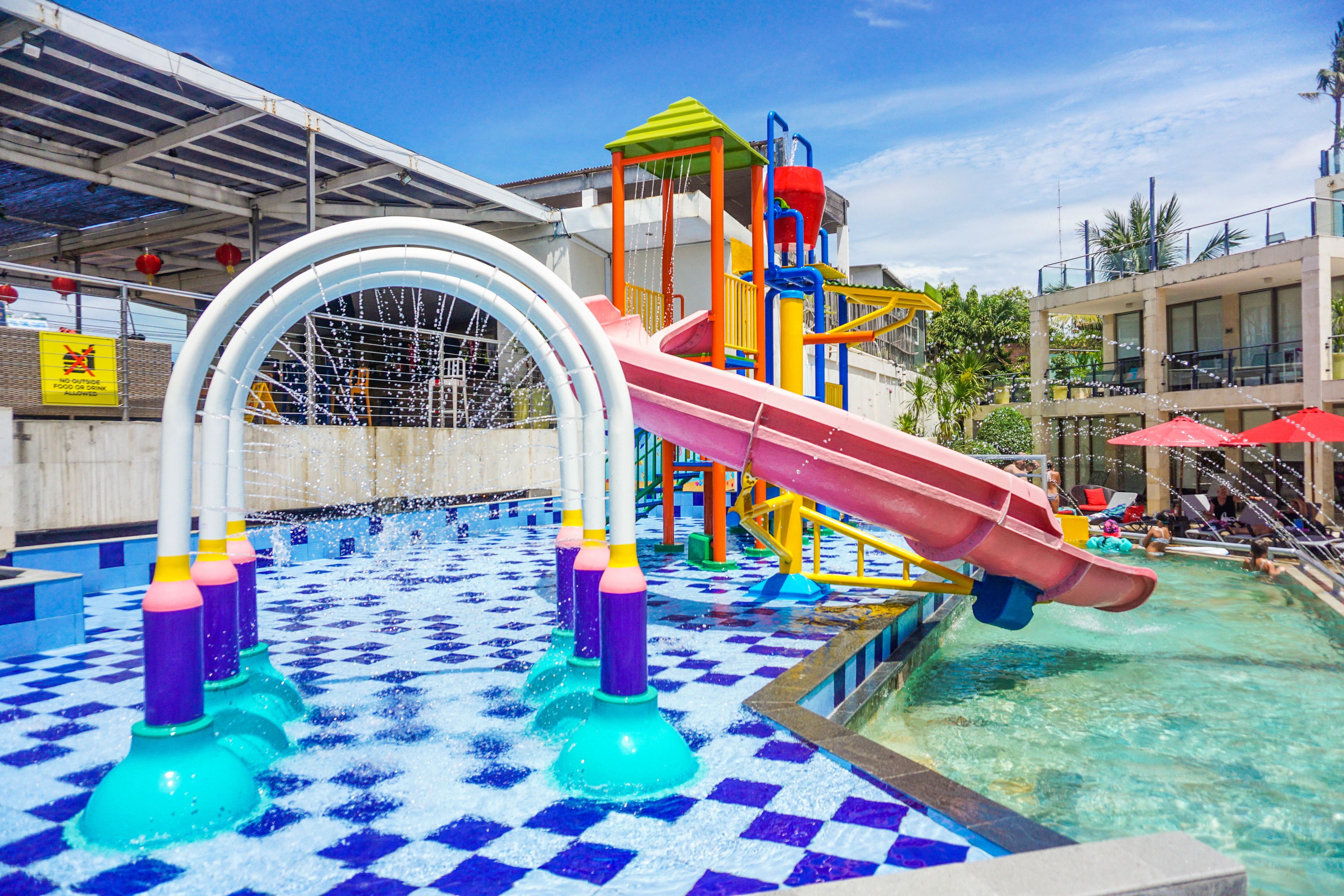 A water park area with a slide, water jets, and a pool.
