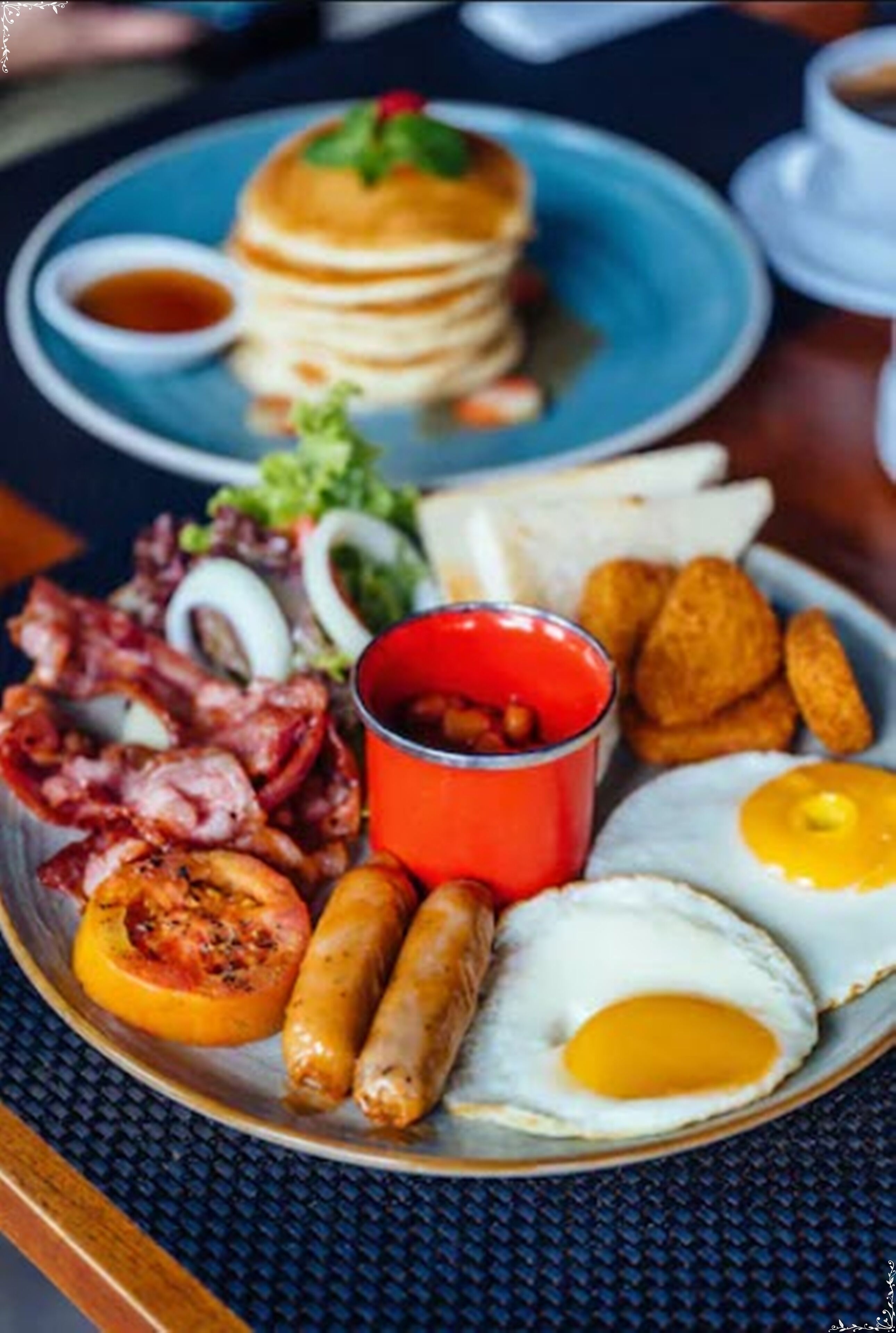 Un plato de desayuno con tortitas, tocino, salchichas, huevos y tostadas.