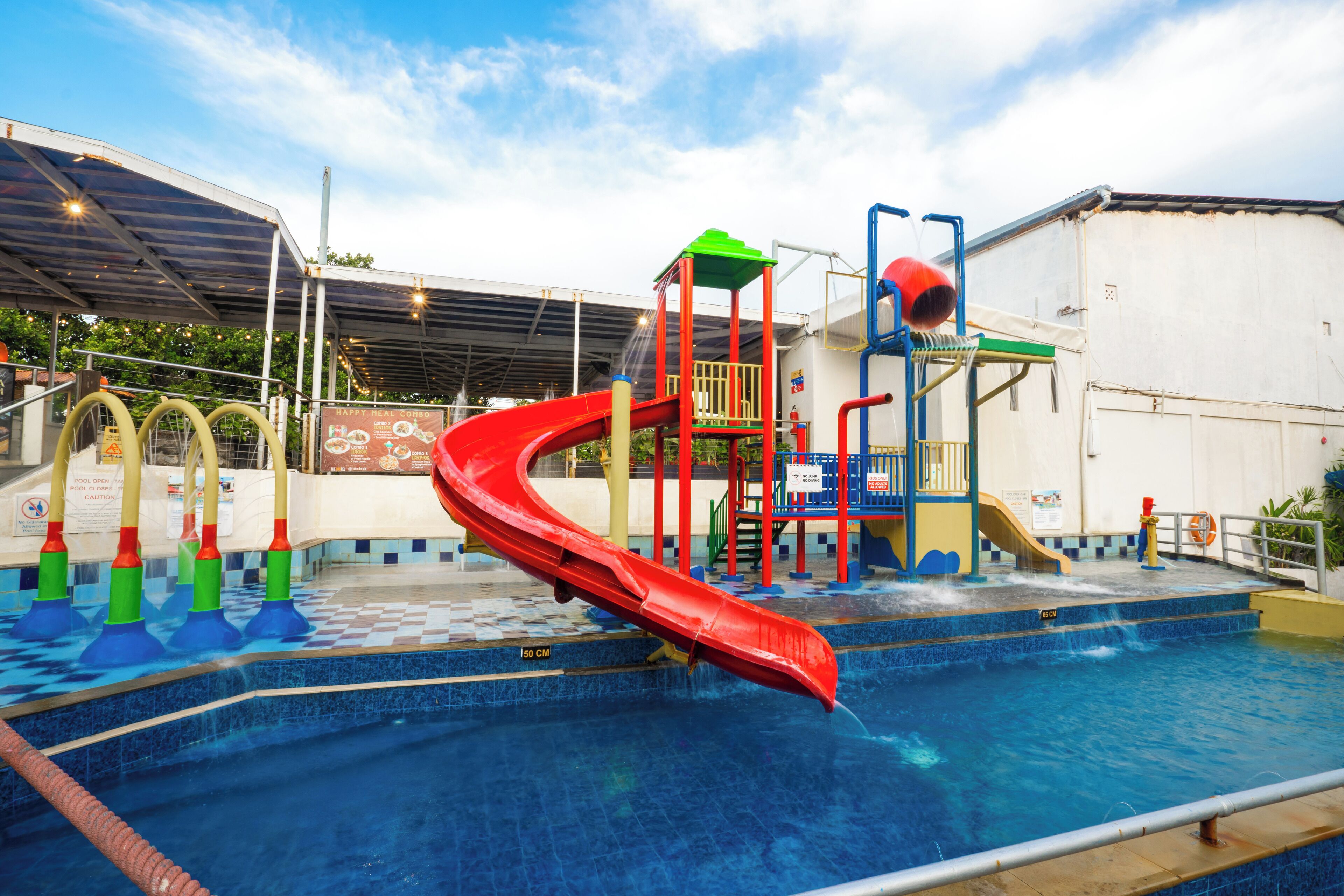 A water park with a red slide, a water play area, and a pool.