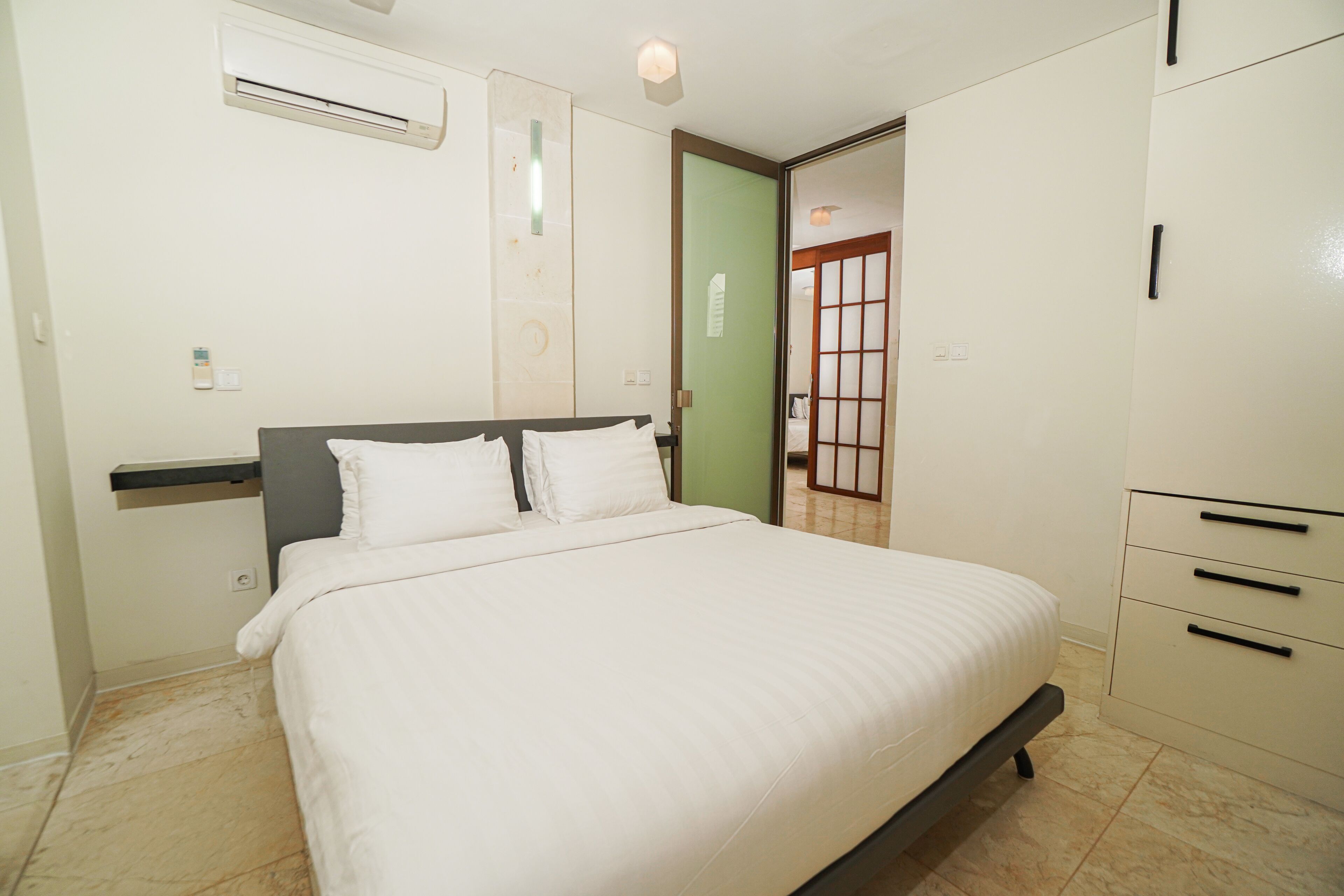 A bedroom with a bed, a wardrobe, a door, and an air conditioning unit.