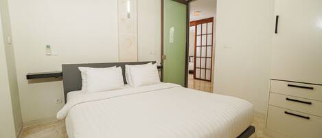 A bedroom with a bed, a wardrobe, a door, and an air conditioning unit.
