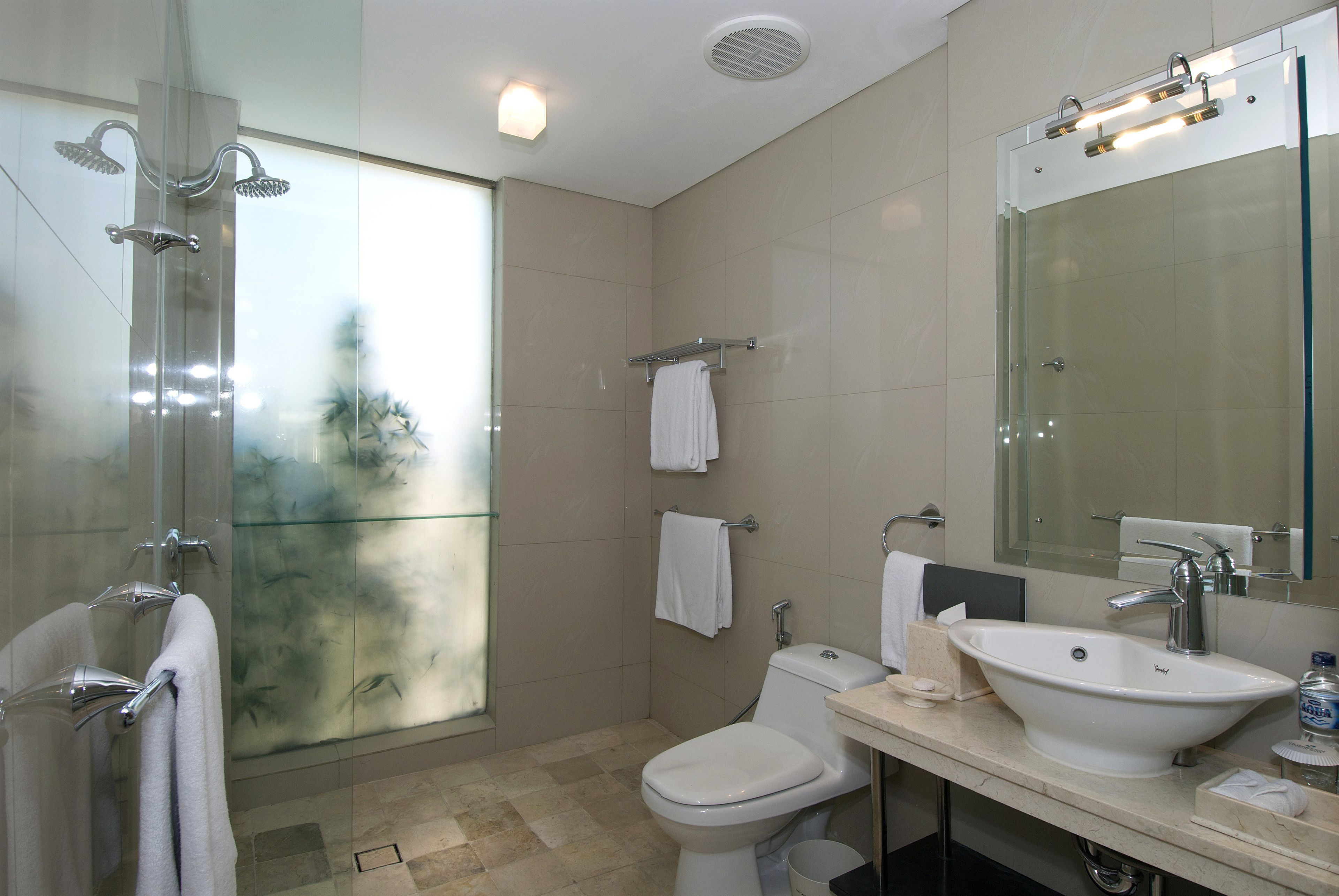 Un baño moderno con cabina de ducha de vidrio, inodoro, lavabo y un espejo grande.