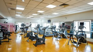 Et fitnesscenter med forskellig træningsudstyr, herunder løbebånd og spinningcykler, stillet op i rækker.