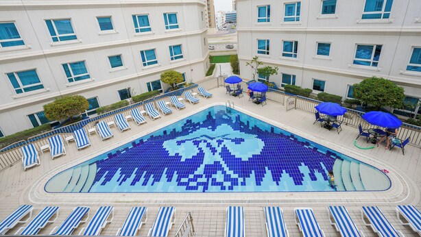 Et hotel med en stor swimmingpool, mange liggestole og parasoller.
