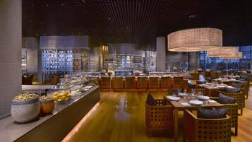 A spacious restaurant with a long counter, wooden chairs, and a high ceiling with a grid pattern.