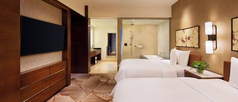 Une chambre d’hôtel avec deux lits, une télévision, une salle de bain avec douche et un bureau.