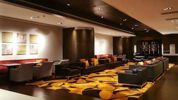 A modern lobby with a long sofa area, a patterned carpet, and wall art.